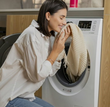 a woman sitting on the floor in front of a washing machine